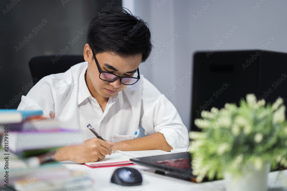 young man studying and writing on notebook with laptop young man studying and writing on notebook with laptop