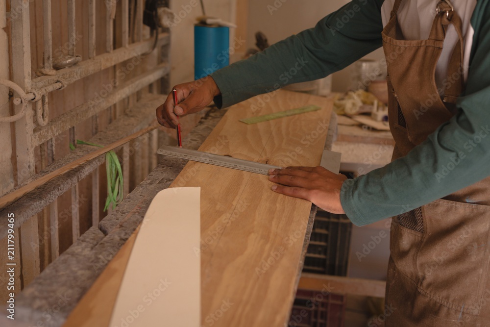 Midsection of man marking on skateboard in workshop Midsection of man marking on skateboard in workshop