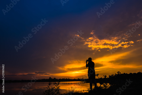 Silhouette photographer at sunset on the lake landscape