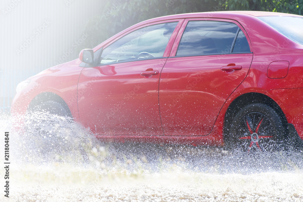 Red car rides on big puddle. Water splash. Red car rides on big puddle. Water splash.