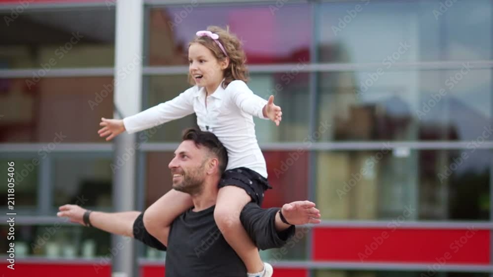 A beautiful curly-haired boy hugs his father from behind behind his shoulders. Father's day, happy family A beautiful curly-haired boy hugs his father from behind behind his shoulders. Father's day, happy family