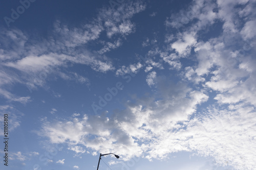 white clouds with overhead street lamp blue sky