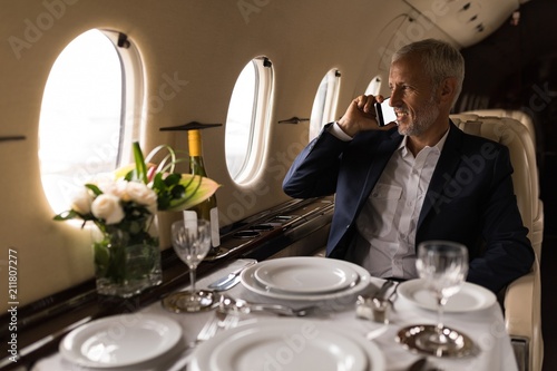 Businessman talking on mobile phone in private jet photo