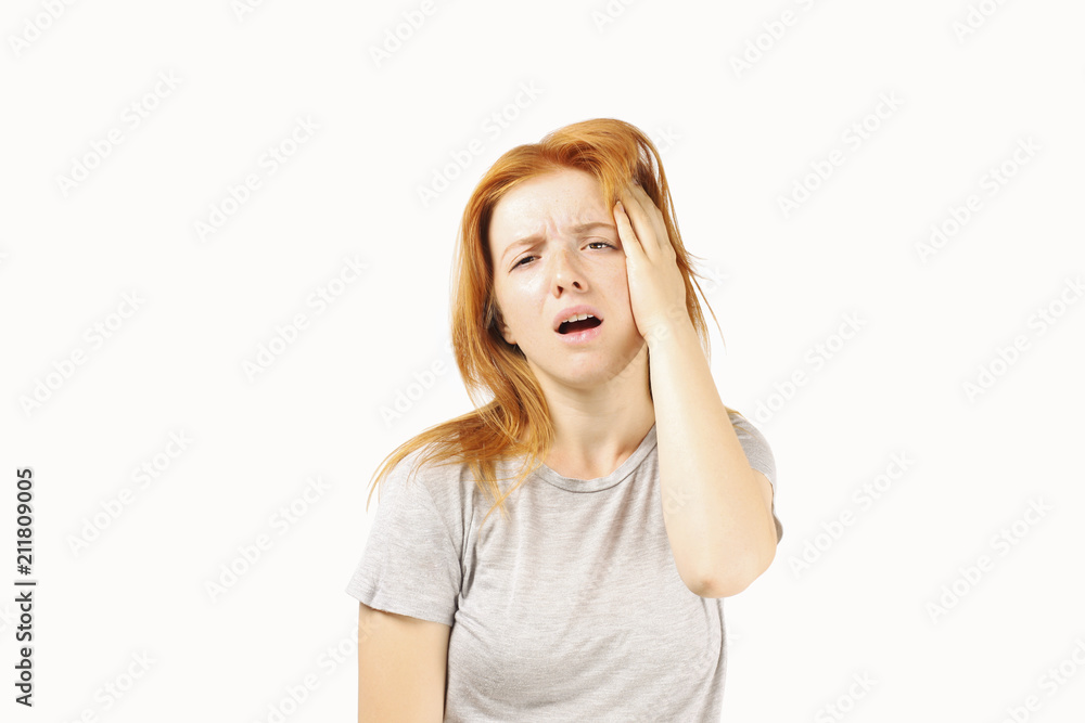 Beautiful redheaded young woman experiencing severe migraine writhing with pain. Pretty female feeling headache holding head. Nonverbal behavior, body language. White background, close up, copy space. Beautiful redheaded young woman experiencing severe migraine writhing with pain. Pretty female feeling headache holding head. Nonverbal behavior, body language. White background, close up, copy space.