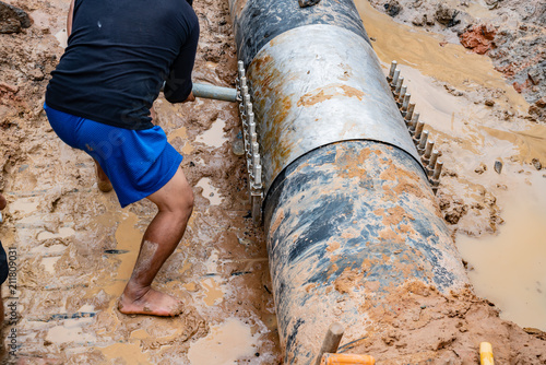 worker lock Cast aluminium cover & PVC Plastic water pipe broken, 600 mm. diameter band with torque bolt screw.
Water PVC Plastic Pipes in Ground during Plumbing Construction site. photo