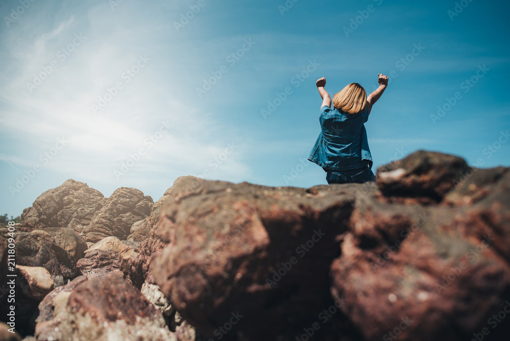 Women sitting on the rock.Strong girl confidence open arms under the beautiful sky at the seaside. Women sitting on the rock.Strong girl confidence open arms under the beautiful sky at the seaside.