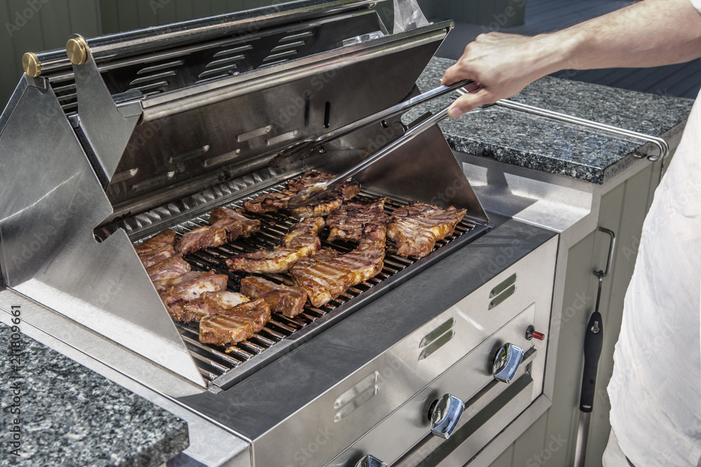 modern outdoor propane gas grill with man turning stakes