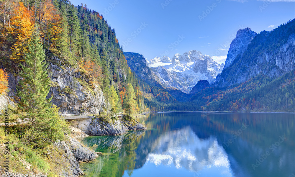 Autumn scenery of Lake Gosausee with snow-capped Dachstein Mountain in background & beautiful reflections on smooth water in Gosau, Austria ~ A dramatic scene of unspoilt nature of Alps on a sunny day