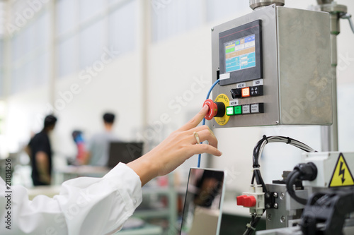 Hand pressing the red emergency button or stop button for industrial machine, Emergency Stop for Safety.