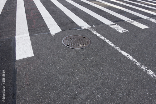 city street walkway crossing white lines manhole cover asphalt tarmac 