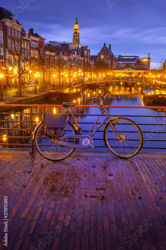 Night view Leiden city center with canal, bridge, bicycles. Street Nieuwe Rijn. View to the Leiden City Hall. Netherlands.