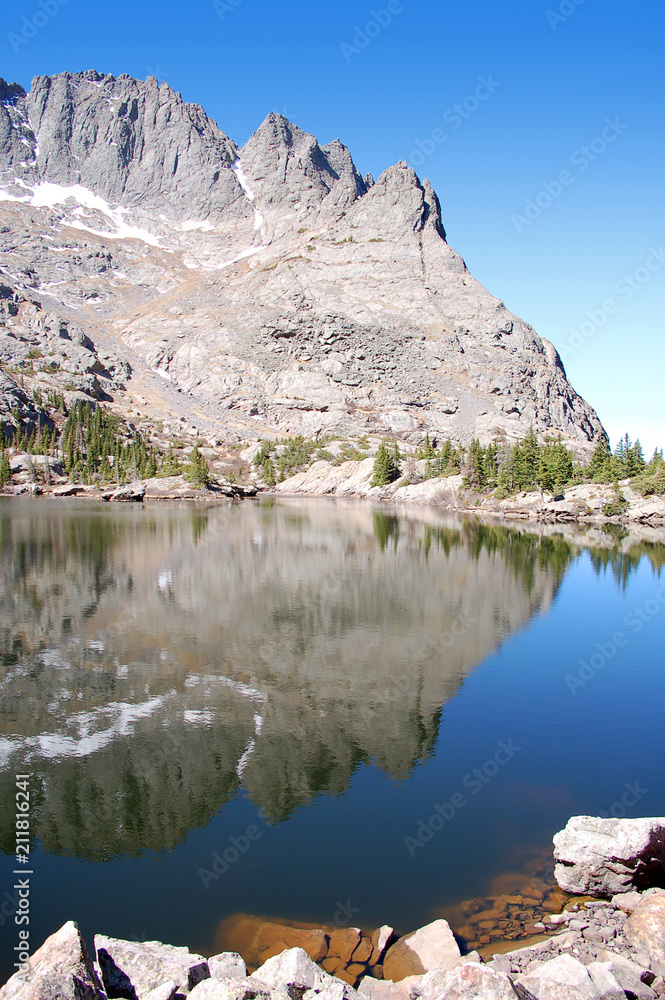 Blue sky and craggy rocks reflected in the pristine waters of South crestone lake in the Sangre De Cristo Mnts of Southern Colorado.