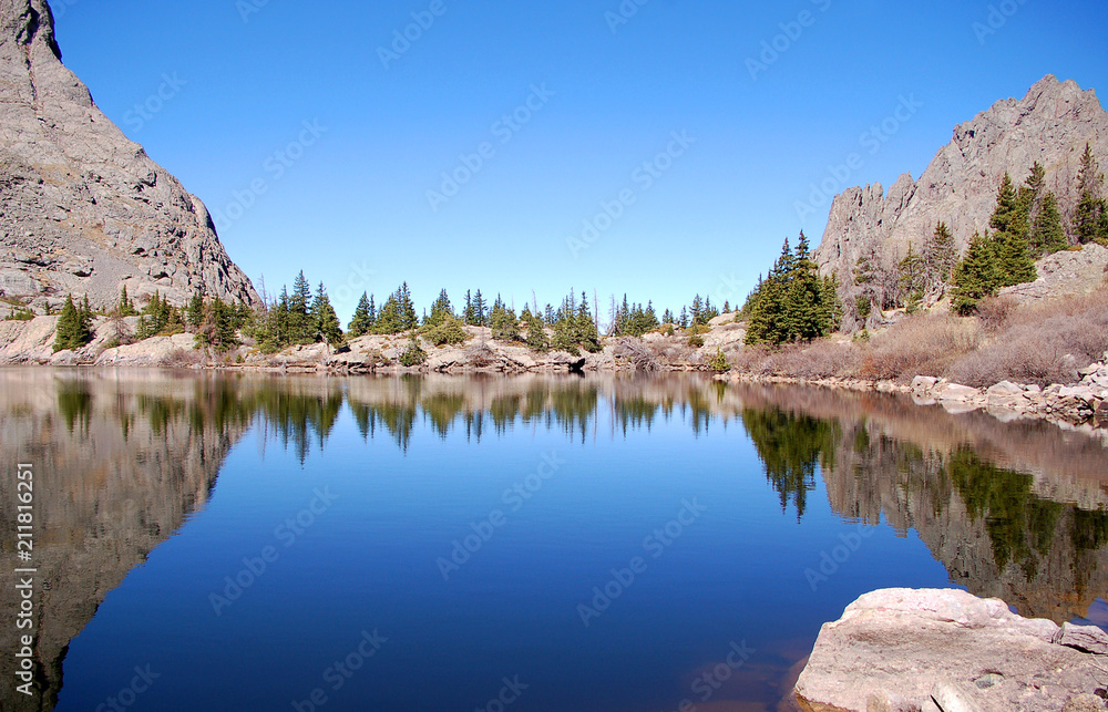 Blue sky and craggy rocks reflected in the pristine waters of South crestone lake in the Sangre De Cristo Mnts of Southern Colorado.