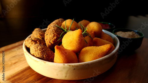 Traditional Brazilian snacks coxinha and quibe on wooden dark background. Selective focus.