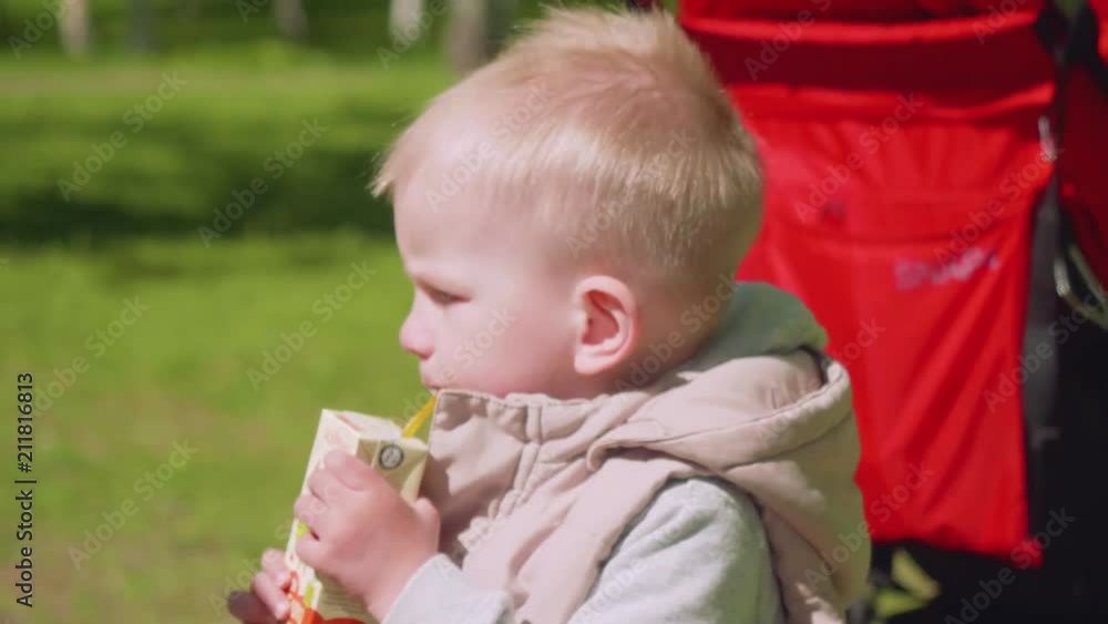 Little blond boy drinks juice with stick Little blond boy drinks juice with stick