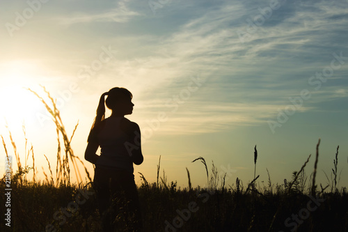 Silhouette of a little girl in the rays of sunset