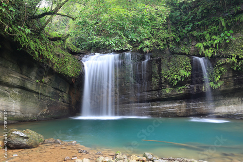Fototapeta Naklejka Na Ścianę i Meble -  A cool refreshing waterfall tumbling down the cliff into an emerald pond hidden in a mysterious forest of lush greenery ~ Scenic view of a beautiful waterfall and intriguing river potholes in Taiwan