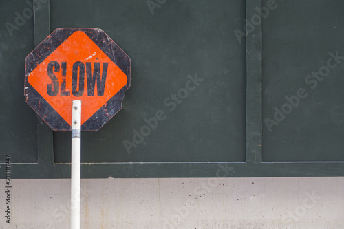 black orange slow sign proper on green wood wall