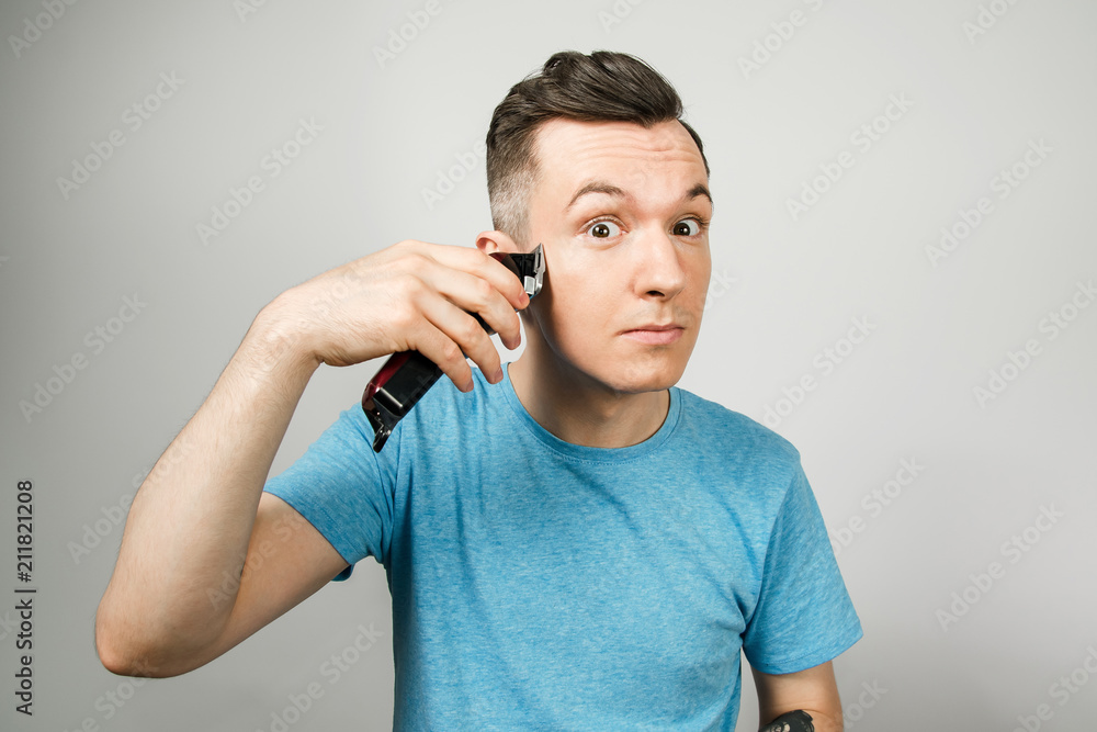Young guy is shaved his beard with a clipper, isolated on white. Young guy is shaved his beard with a clipper, isolated on white.