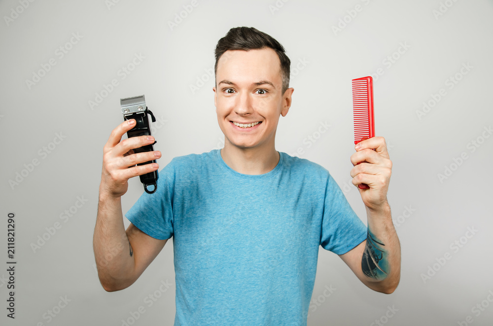 Barber smiles and holds clipper and comb, isolated on a white background. Barber smiles and holds clipper and comb, isolated on a white background.