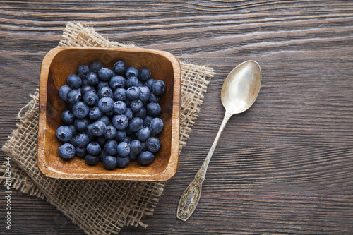 heap ripe sweet blueberries and spoon on wooden table top view