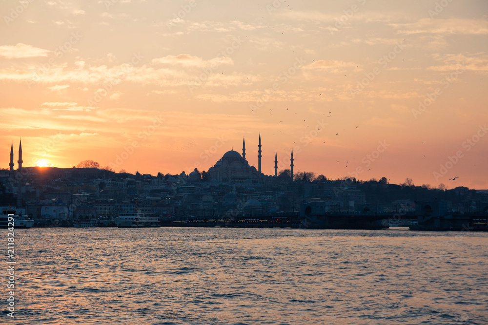 Cityscape of Istanbul with silhouettes of ancient mosques and minarets at sunset on blur background with ship in front. Panoramic view on the old city. Istanbul sunset. selective focus, unfocus