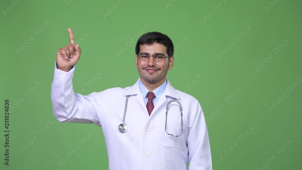 Young handsome Persian man doctor pointing up Young handsome Persian man doctor pointing up