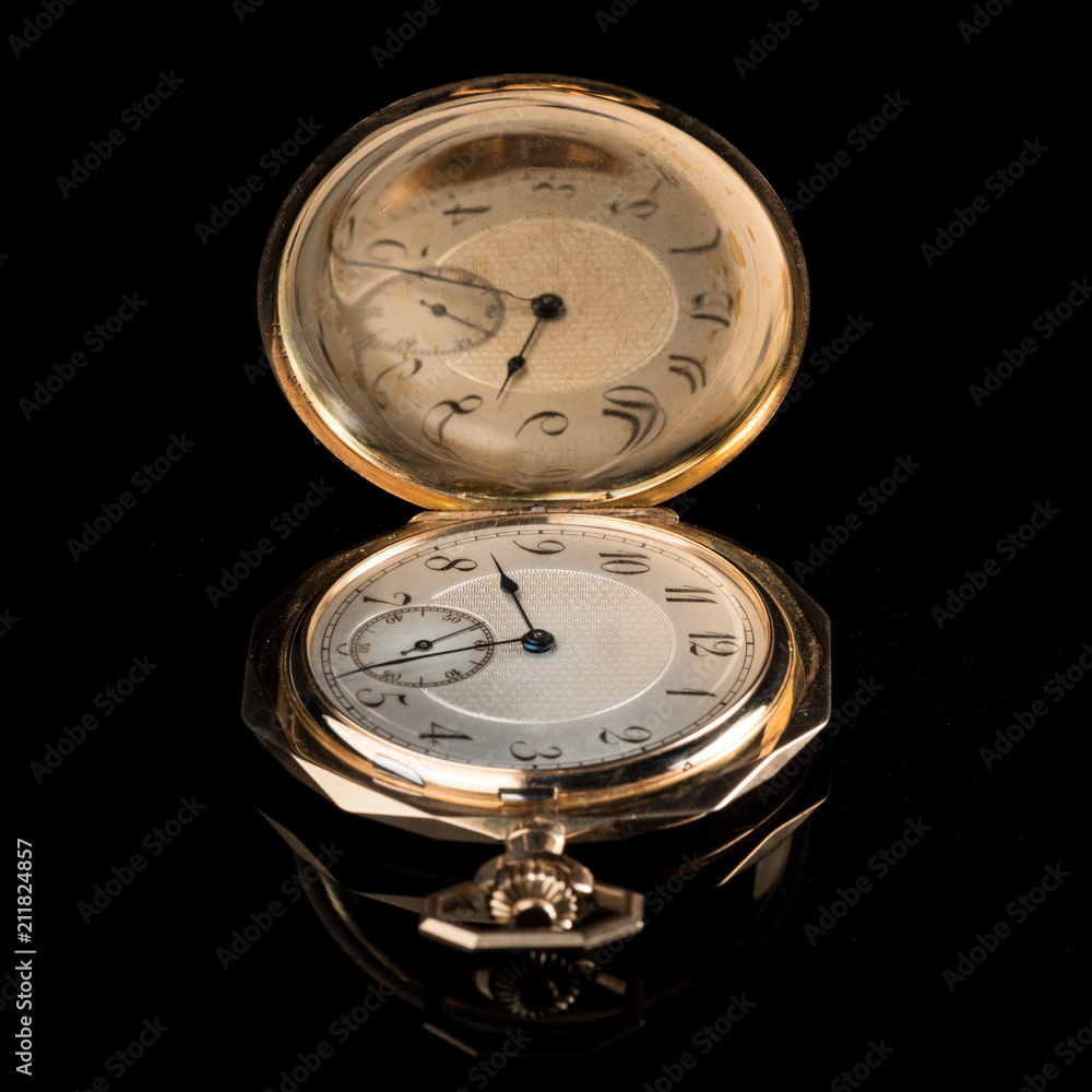 Old golden pocket watch on a black reflective surface Old golden pocket watch on a black reflective surface