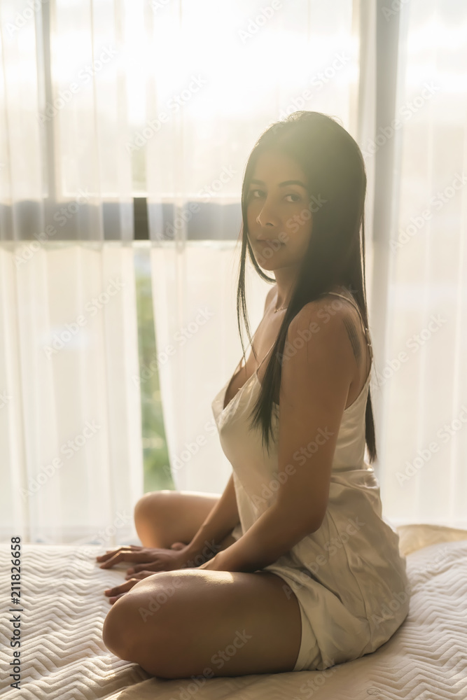 Sexy Asian woman in bed at sunset Sexy Asian woman in bed at sunset