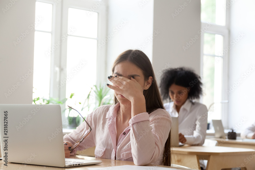 Stressed female employee messaging eyes trying to relieve pain, having break from work, tired worker suffering from headache or eyestrain, reducing tension and calming down. Concept of overwork Stressed female employee messaging eyes trying to relieve pain, having break from work, tired worker suffering from headache or eyestrain, reducing tension and calming down. Concept of overwork