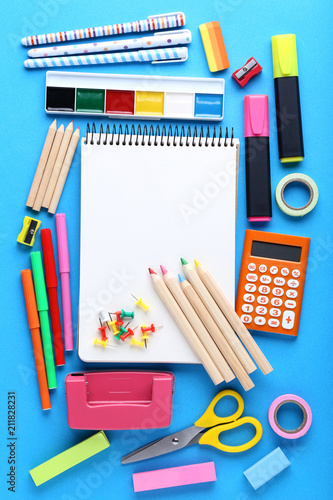 School supplies with blank sheet of paper on blue background