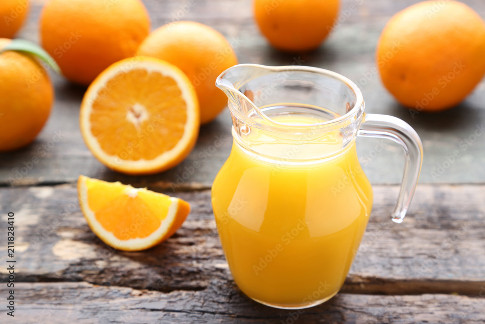 Orange fruit with jug of juice on grey wooden table Orange fruit with jug of juice on grey wooden table