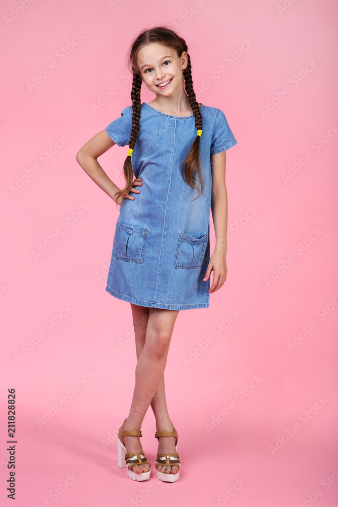 Young girl in denim dress on pink background Young girl in denim dress on pink background