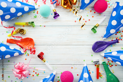 Birthday party caps, blowers and balloons on wooden table