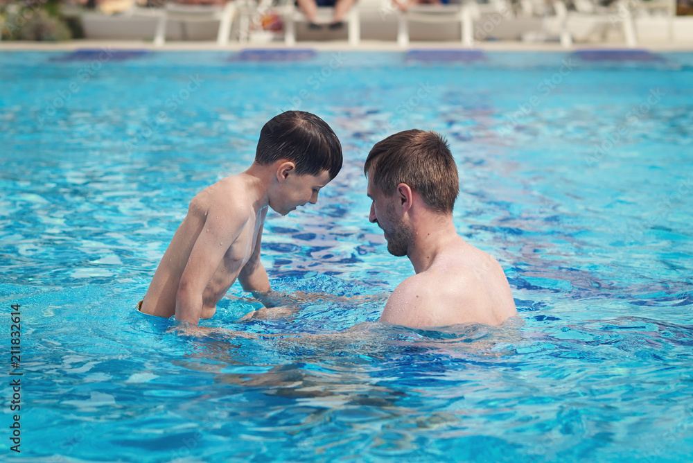 Father and son having fun in the swimming pool at the hotel. Father and son having fun in the swimming pool at the hotel.
