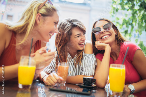 Three beautiful friends in a cafe having fun