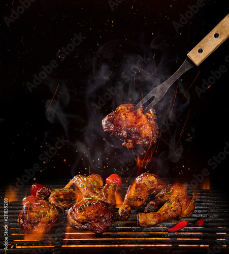 Chicken legs and wings on the grill with flames