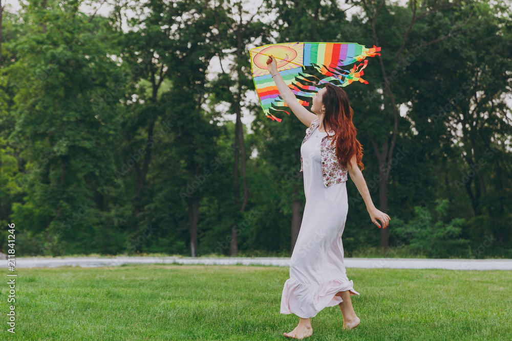 Attractive joyful smiling woman in light dress running, play with colorful kite and have fun in green park. Mother, little kid daughter. Mother's Day, love family, parenthood, childhood concept.