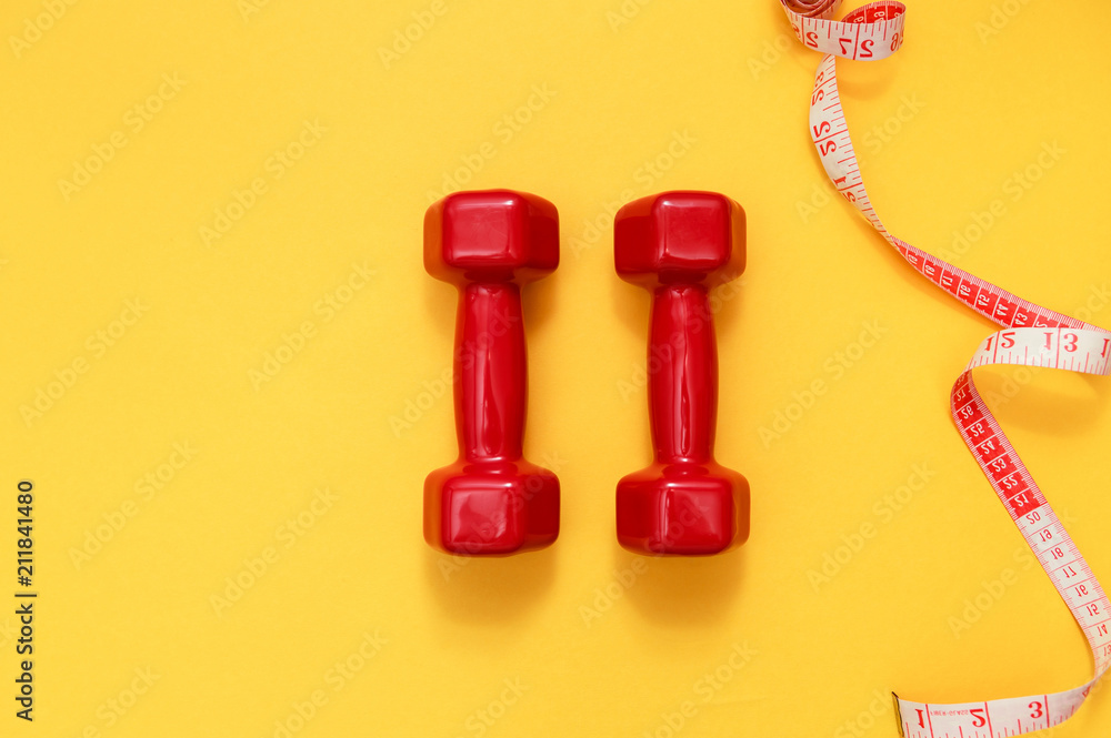 Two red dumbbells and tape measure. Fitness concept Two red dumbbells and tape measure. Fitness concept