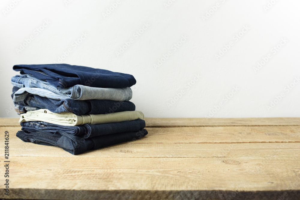 Stack of jeans in a living room setting with a white wall background. Stack of jeans in a living room setting with a white wall background.
