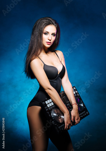 Young, beautiful and sexy dj girl playing music on a disco party in a night club