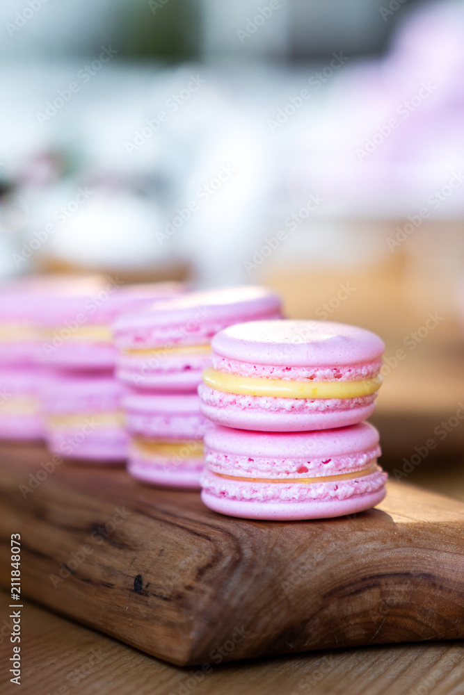 pink macaroon with lemon filling lie on a wooden board. pink macaroon with lemon filling lie on a wooden board.