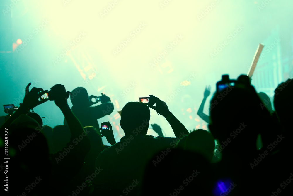 People take pictures with point and shoot cameras and cell phones at a rave party concert