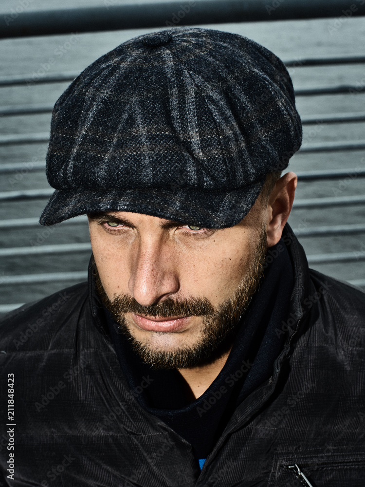 Beautiful portrait of a man in a cap. Cap of different colors and shapes. Autumn portrait, clouds behind and stormy sky. Scarf around the neck in the color of the cap. Face severe, serious. Beautiful portrait of a man in a cap. Cap of different colors and shapes. Autumn portrait, clouds behind and stormy sky. Scarf around the neck in the color of the cap. Face severe, serious.