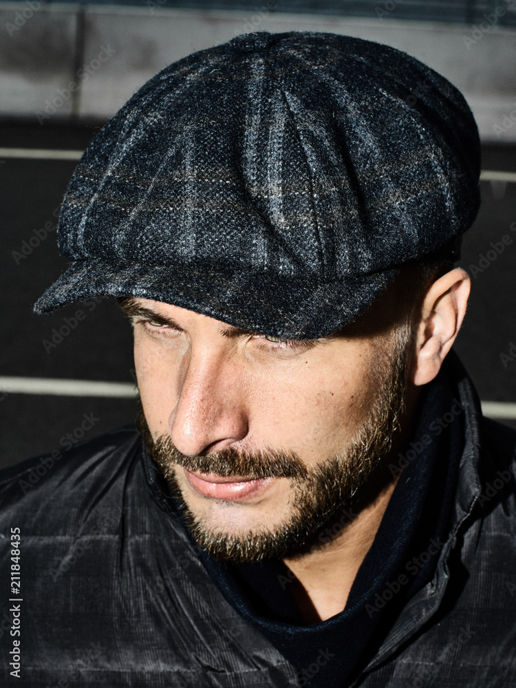 Beautiful portrait of a man in a cap. Cap of different colors and shapes. Autumn portrait, clouds behind and stormy sky. Scarf around the neck in the color of the cap. Face severe, serious. Beautiful portrait of a man in a cap. Cap of different colors and shapes. Autumn portrait, clouds behind and stormy sky. Scarf around the neck in the color of the cap. Face severe, serious.