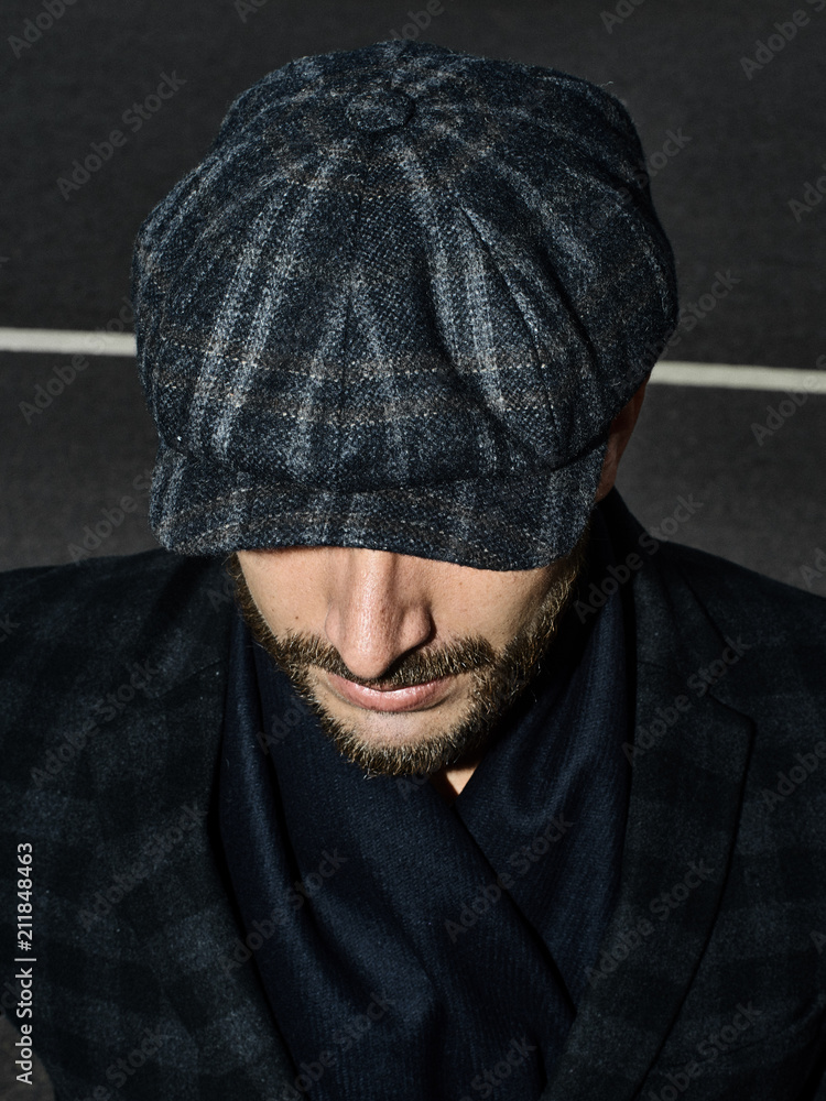 Beautiful portrait of a man in a cap. Cap of different colors and shapes. Autumn portrait, clouds behind and stormy sky. Scarf around the neck in the color of the cap. Face severe, serious. Beautiful portrait of a man in a cap. Cap of different colors and shapes. Autumn portrait, clouds behind and stormy sky. Scarf around the neck in the color of the cap. Face severe, serious.