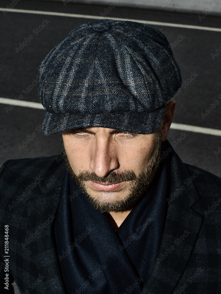 Beautiful portrait of a man in a cap. Cap of different colors and shapes. Autumn portrait, clouds behind and stormy sky. Scarf around the neck in the color of the cap. Face severe, serious. Beautiful portrait of a man in a cap. Cap of different colors and shapes. Autumn portrait, clouds behind and stormy sky. Scarf around the neck in the color of the cap. Face severe, serious.