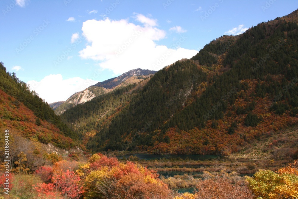 Hiking through the Min Mountains, surrounded by the colorful fall foliage in Jiuzhaigou Valley National Park of Sichuan, China.