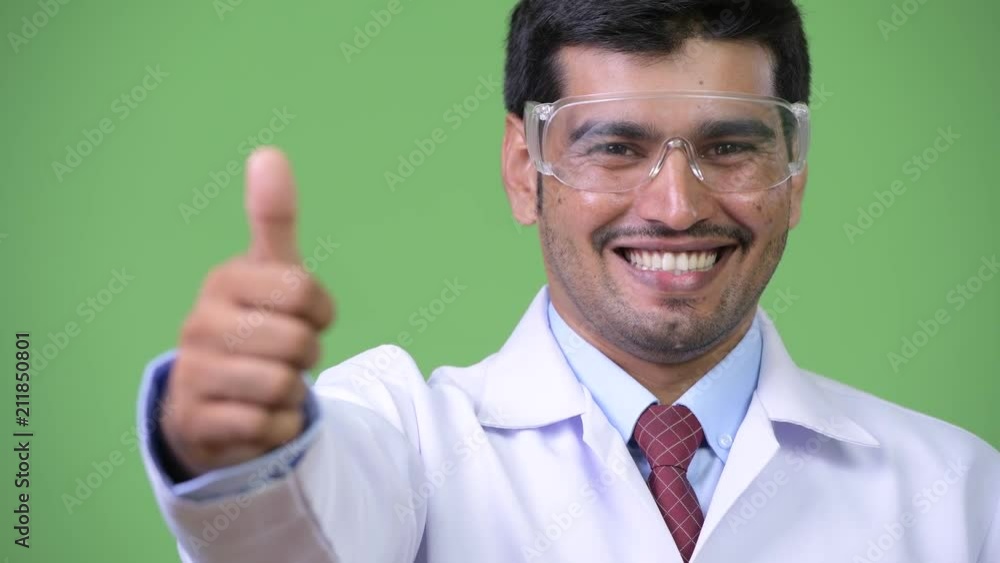 Young handsome Persian man doctor wearing protective glasses giving thumbs up Young handsome Persian man doctor wearing protective glasses giving thumbs up
