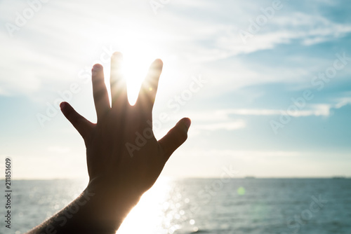 Hand touching sun during sunset background success, peace, freedom and hope concept